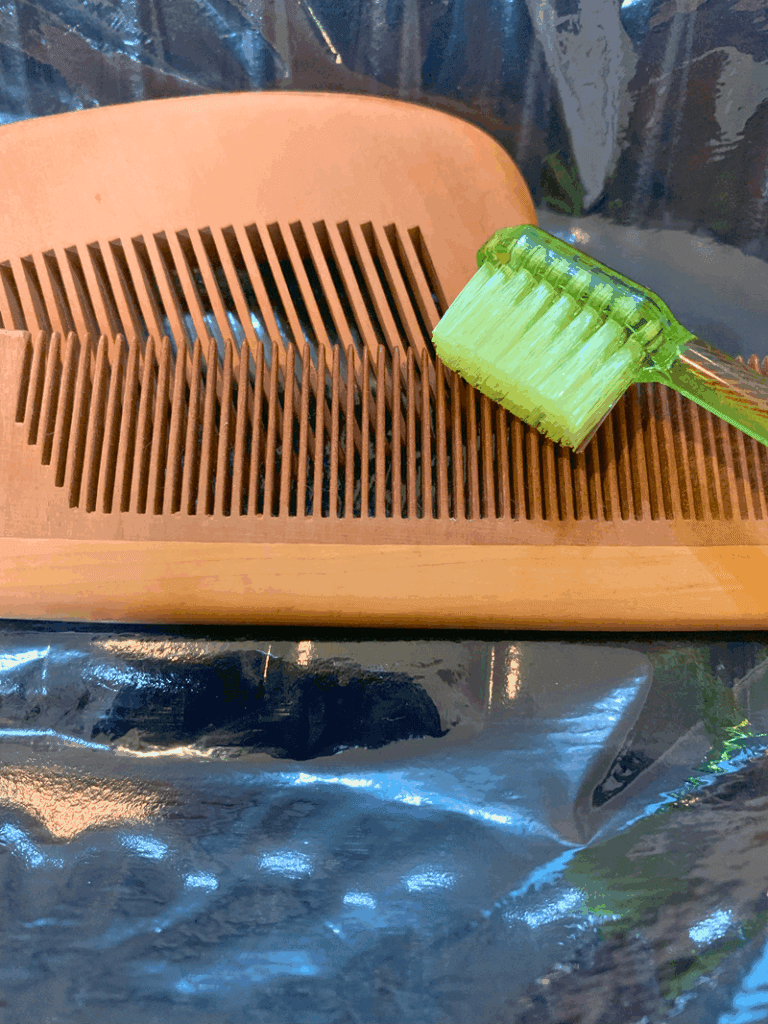 歯ブラシでつげ櫛の歯の間の汚れを落とす