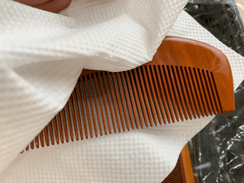 つげ櫛に馴染ませた椿油をふき取る