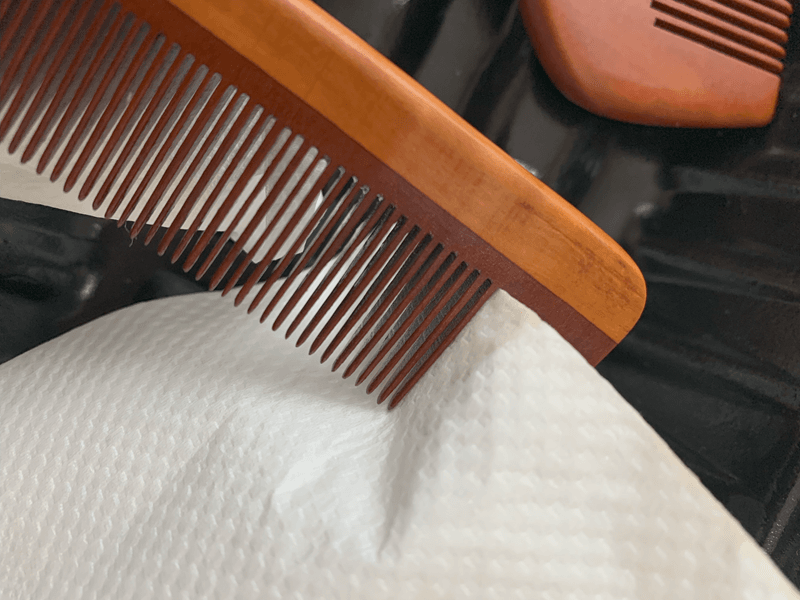 つげ櫛の櫛歯の間の椿油をふき取る